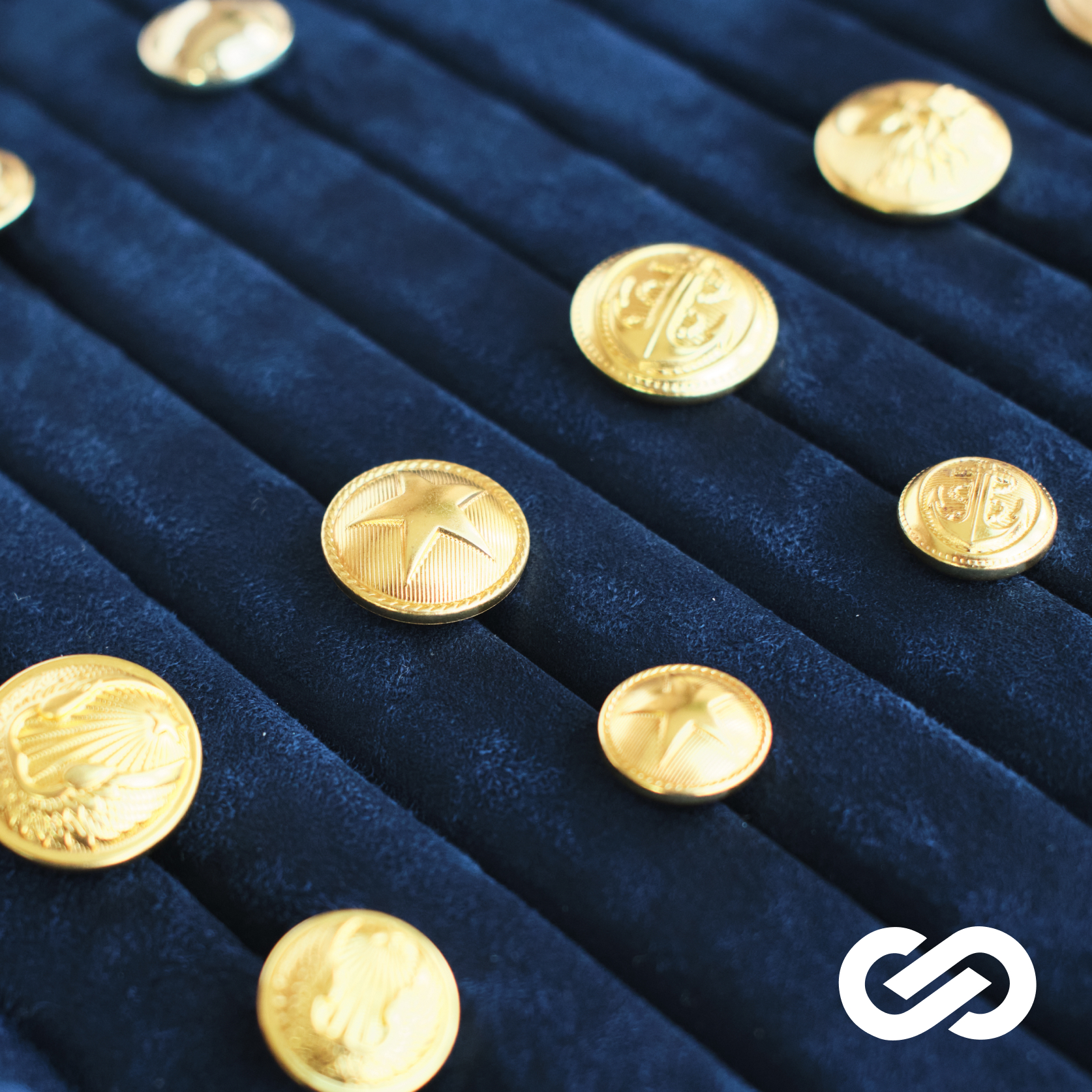 Tray of gold identity buttons and accessories representing Infin8te craftsmanship